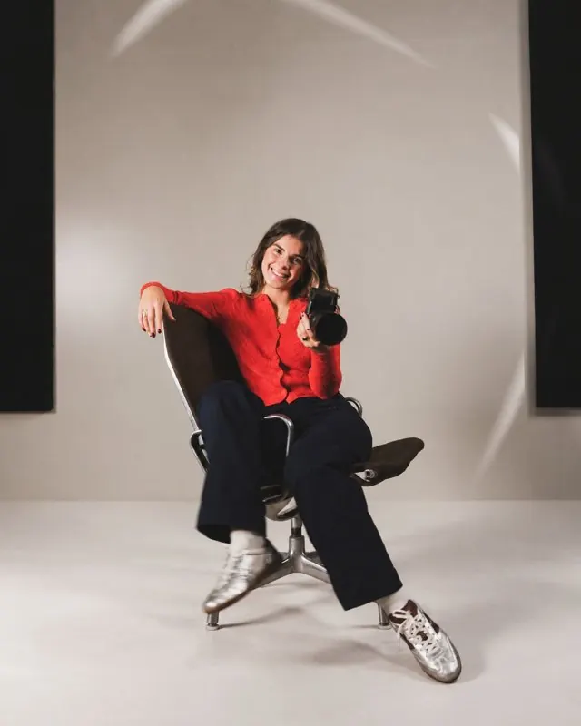 Angèle assise dans un fauteuil, appareil photo à la main